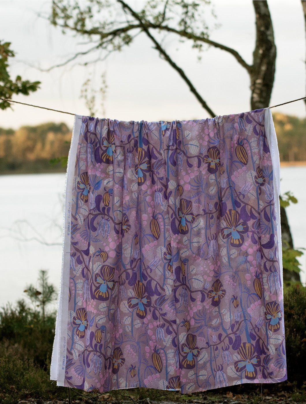 Blommigt tyg som hänger på en lina som en gardin. Design skapad av By Ulrika G