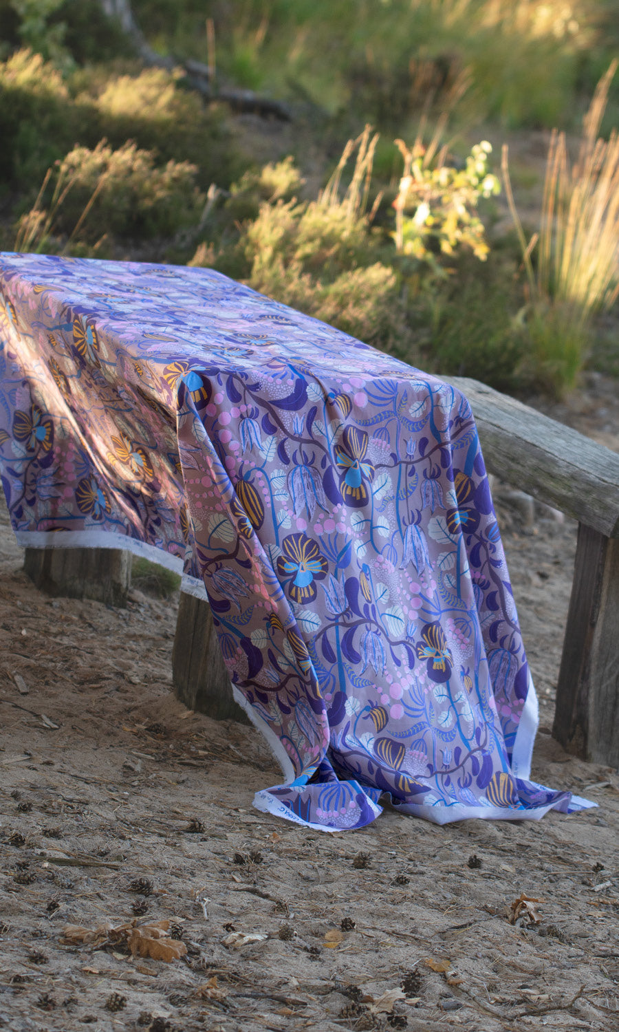 Blommig mönstrat tyg som duk på ett träbord på strande vid sjön