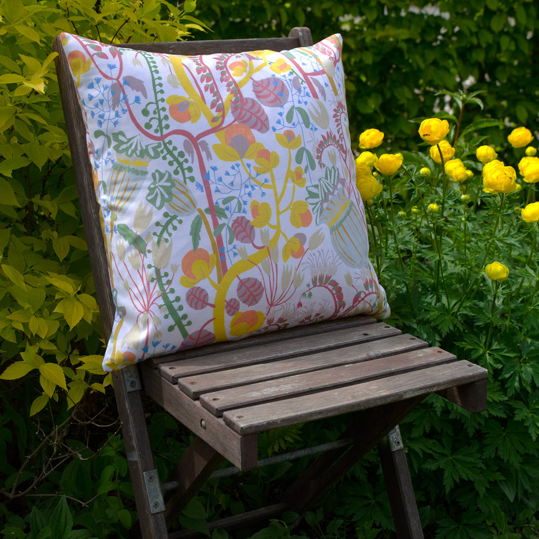 By Ulrika G - Kudde 45x45 cm med mönstret  En sommar i dalarna på en stol i en trädgård