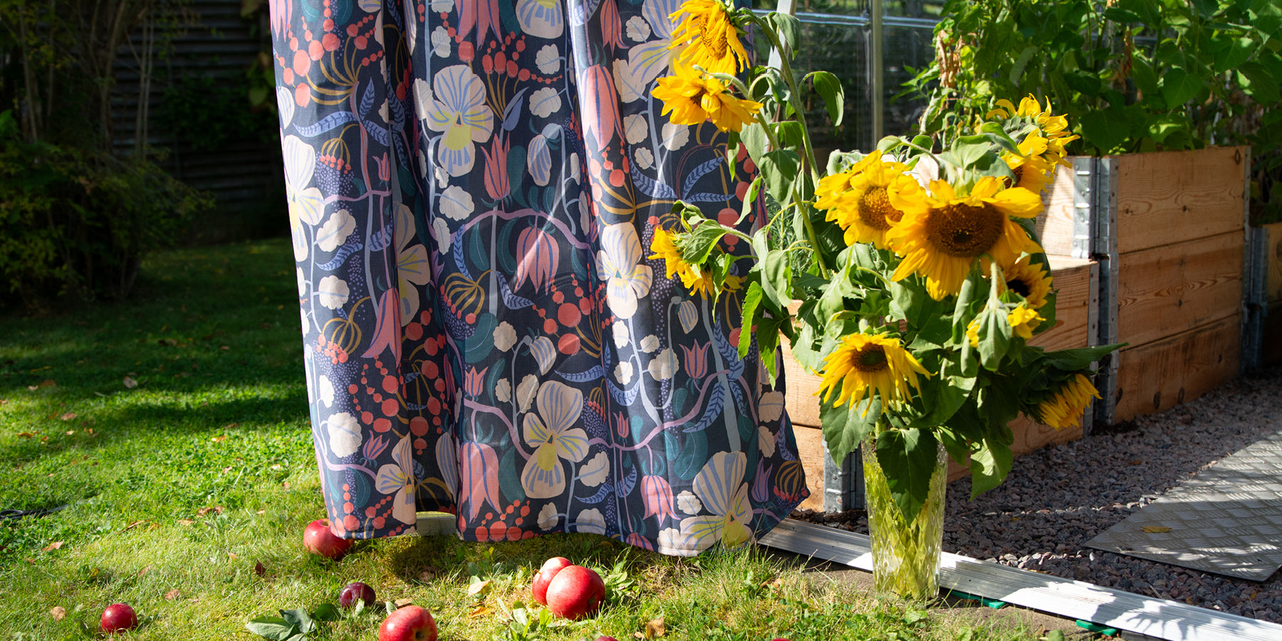 Blommig ljus bommullsgardin med designad av By Ulrika G hänger i växthuset