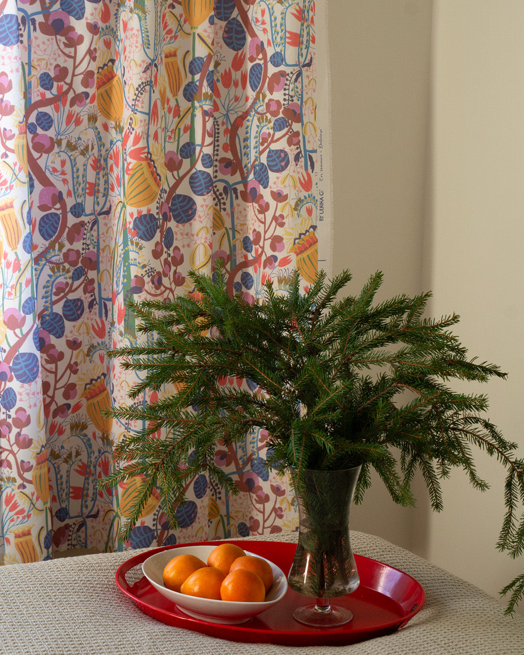 blommig mönstrad gardin i sovrummet med celementiner och granris