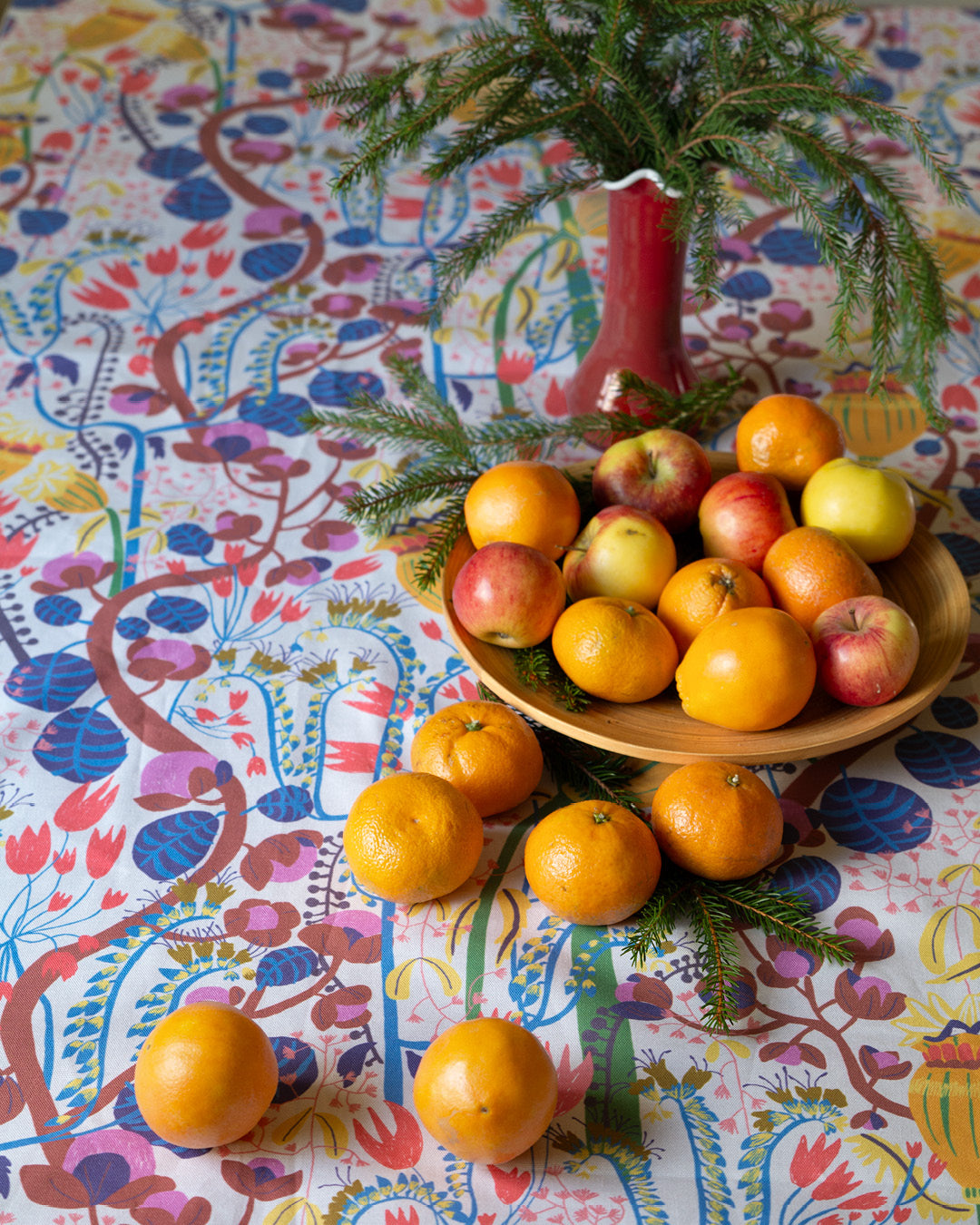 dukning med blommig mönstrad duk, celementiner och granris