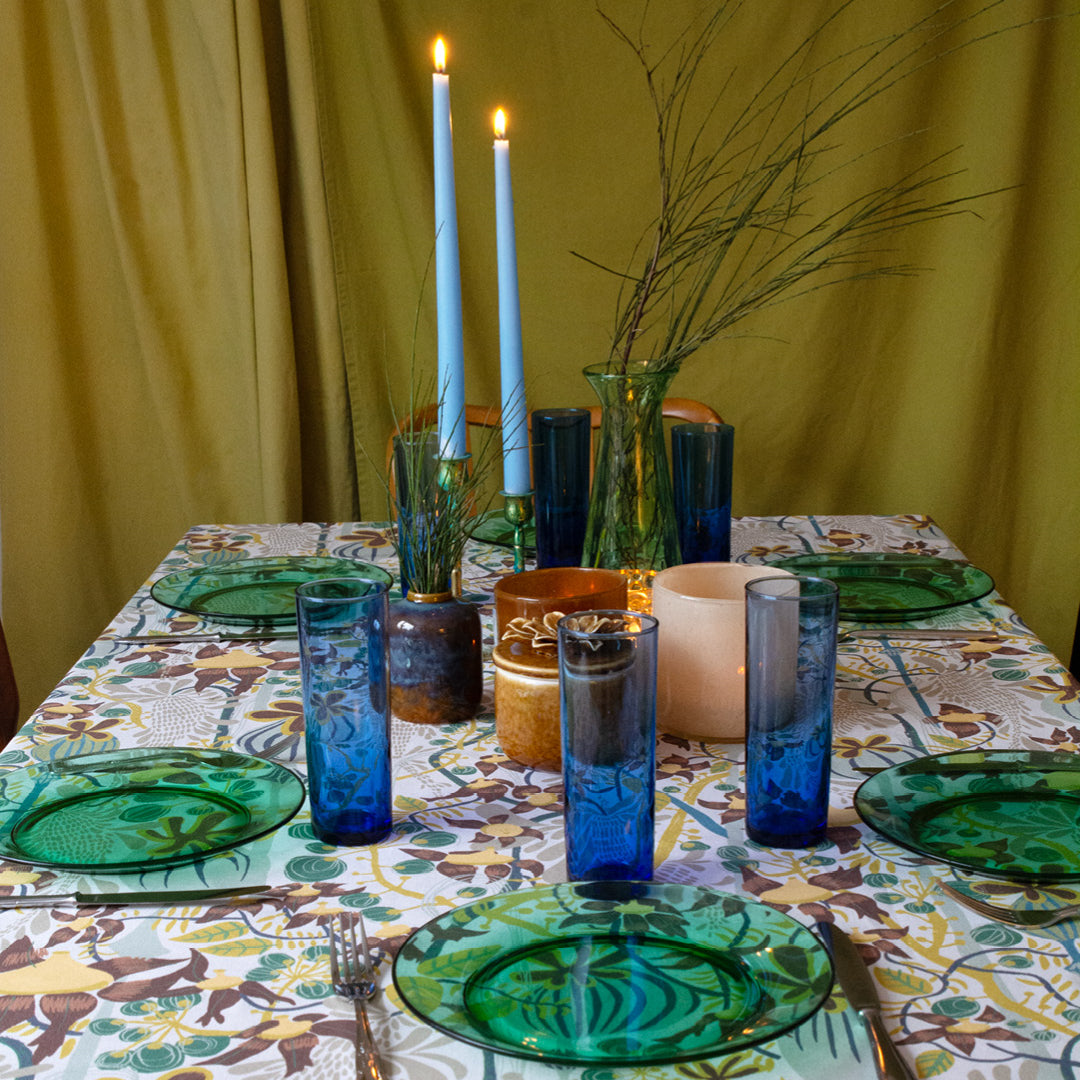 Vårigdukning  med blommigt tyg som duk, gröna tallrikar och blå glas.