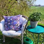 Blommig kudde i en rottingfåtölj vid en åker.