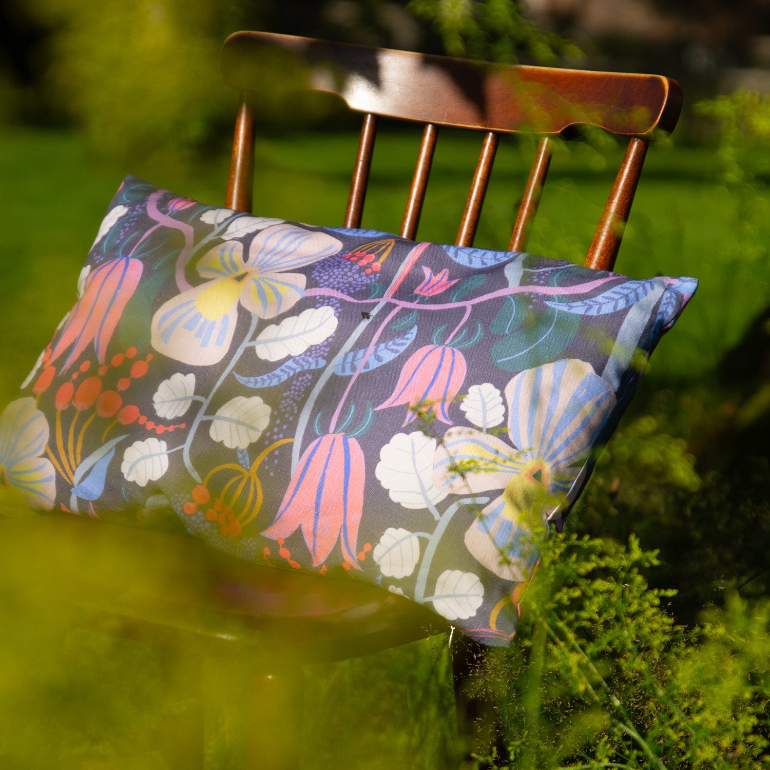 Blommig mönstrad kudde på en stol i trädgården