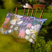 Blommig mönstrad kudde på en stol i trädgården