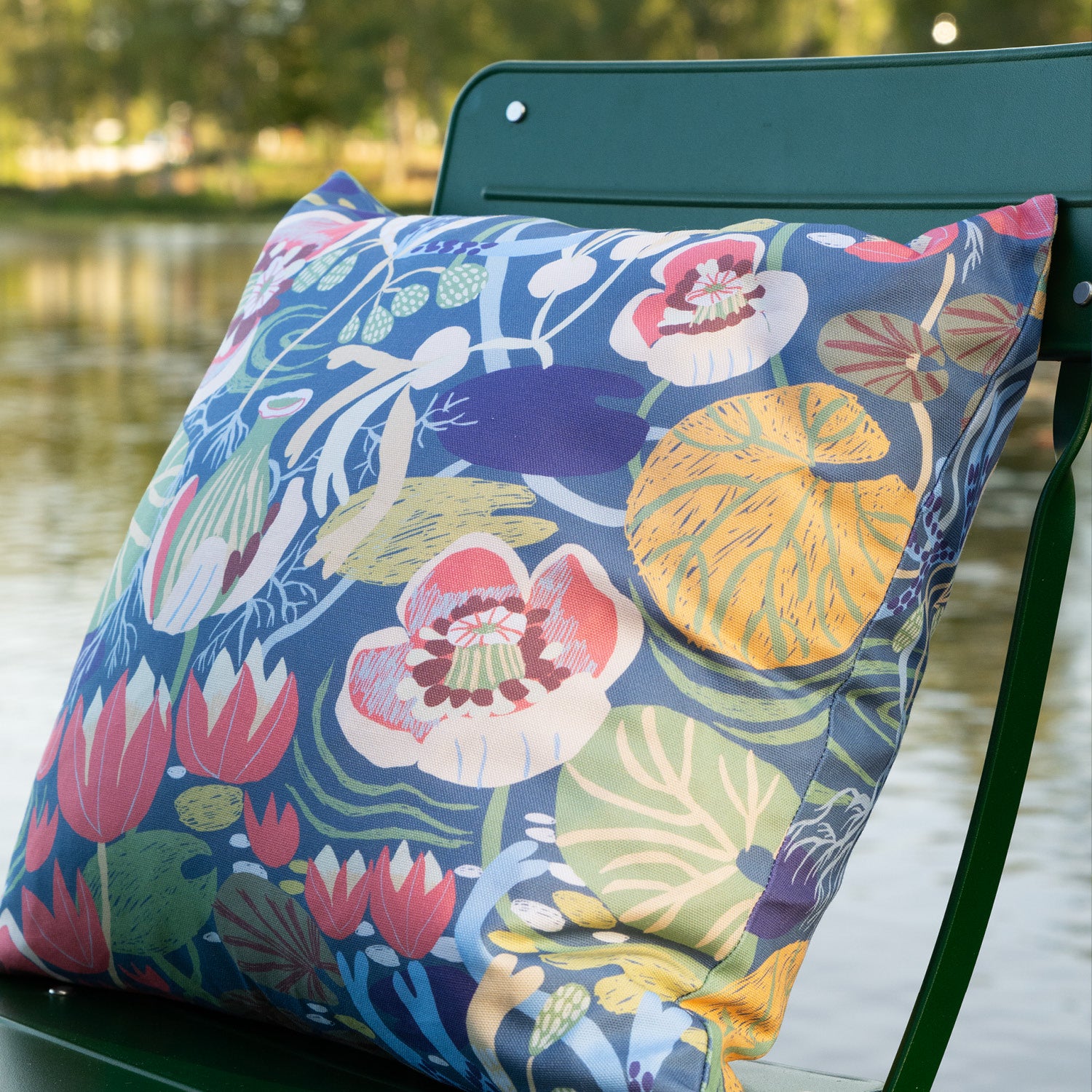 Blommig mönstrad kudde på en stol vid sjön