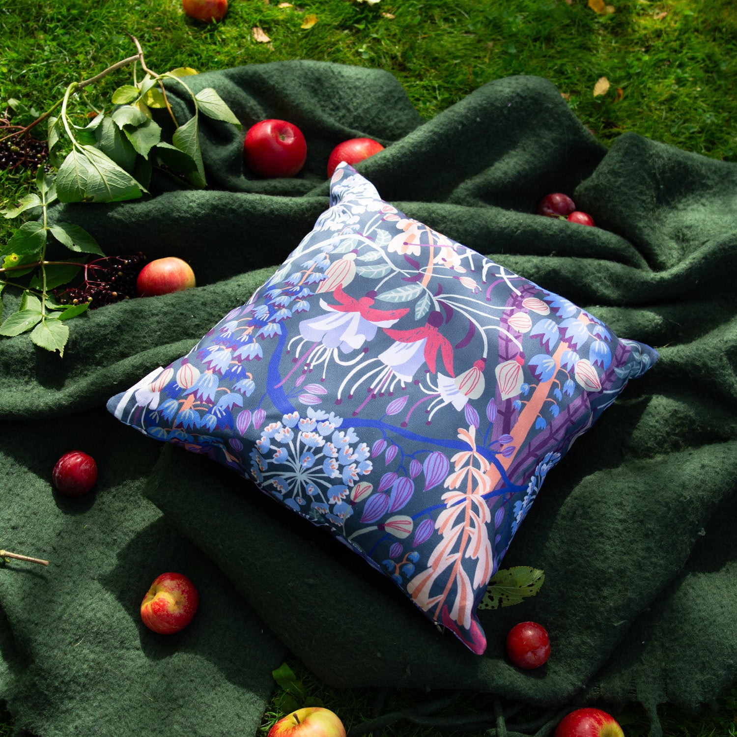 Blommig mönstrad kudde på en filt i trädgården.