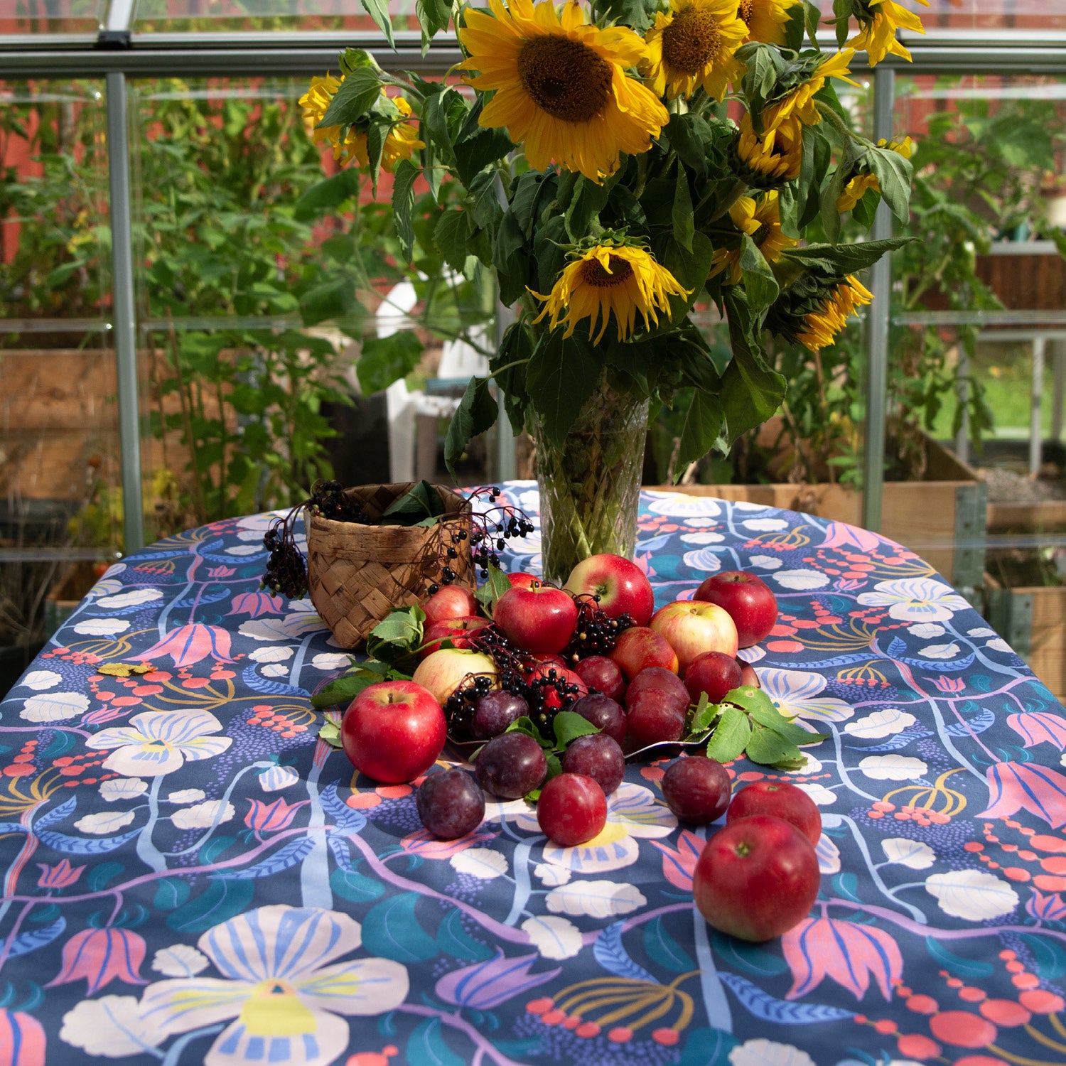 Dukning med mönstrad blommig tyg med solrosor och äpplen