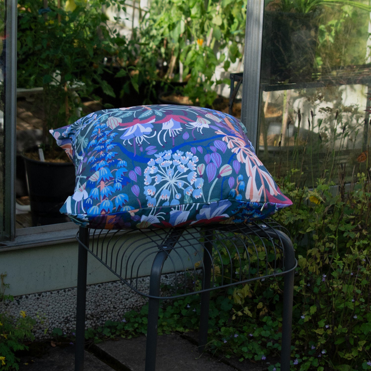 Mönstrad blommig kudde på en pall i trädgården.