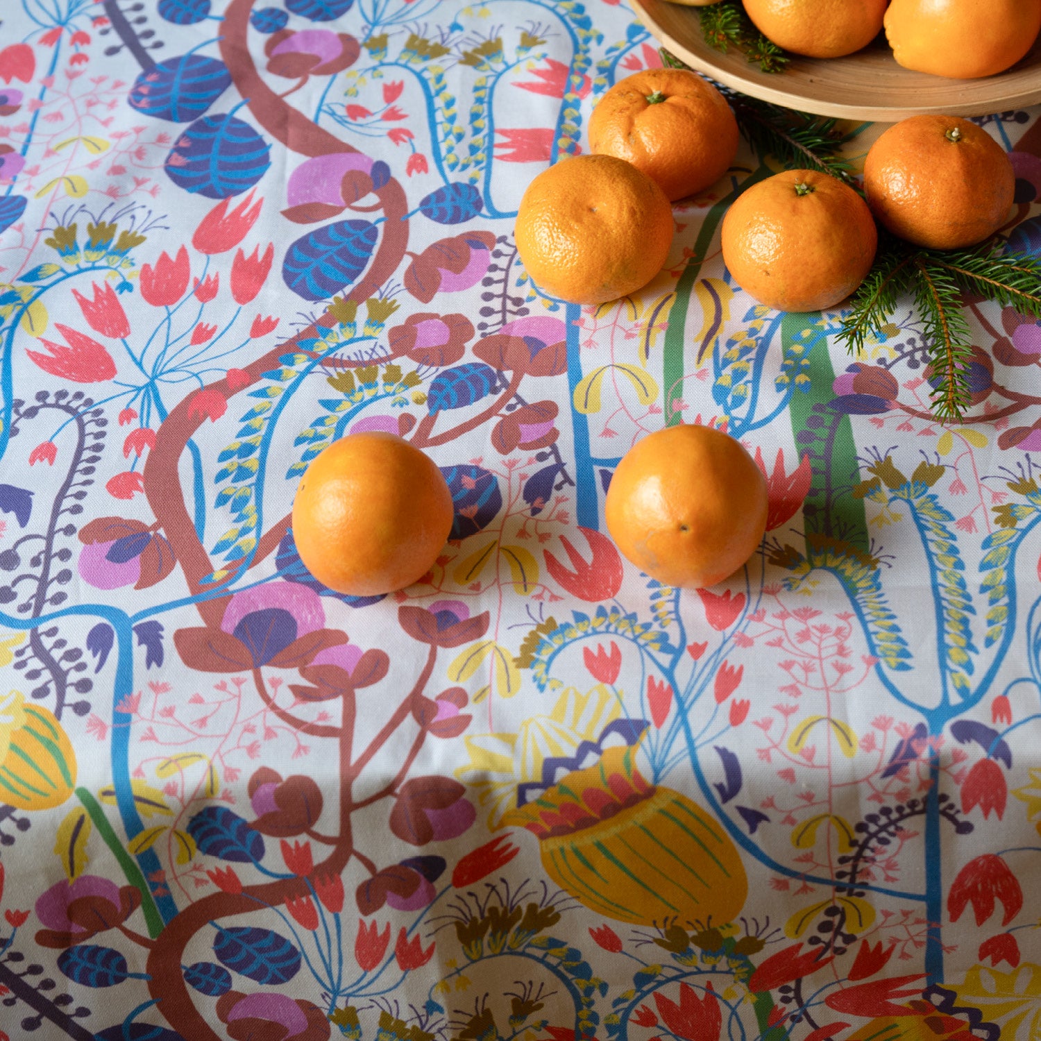 Mönstrad blommig tyg som duk med clementiner i en skål