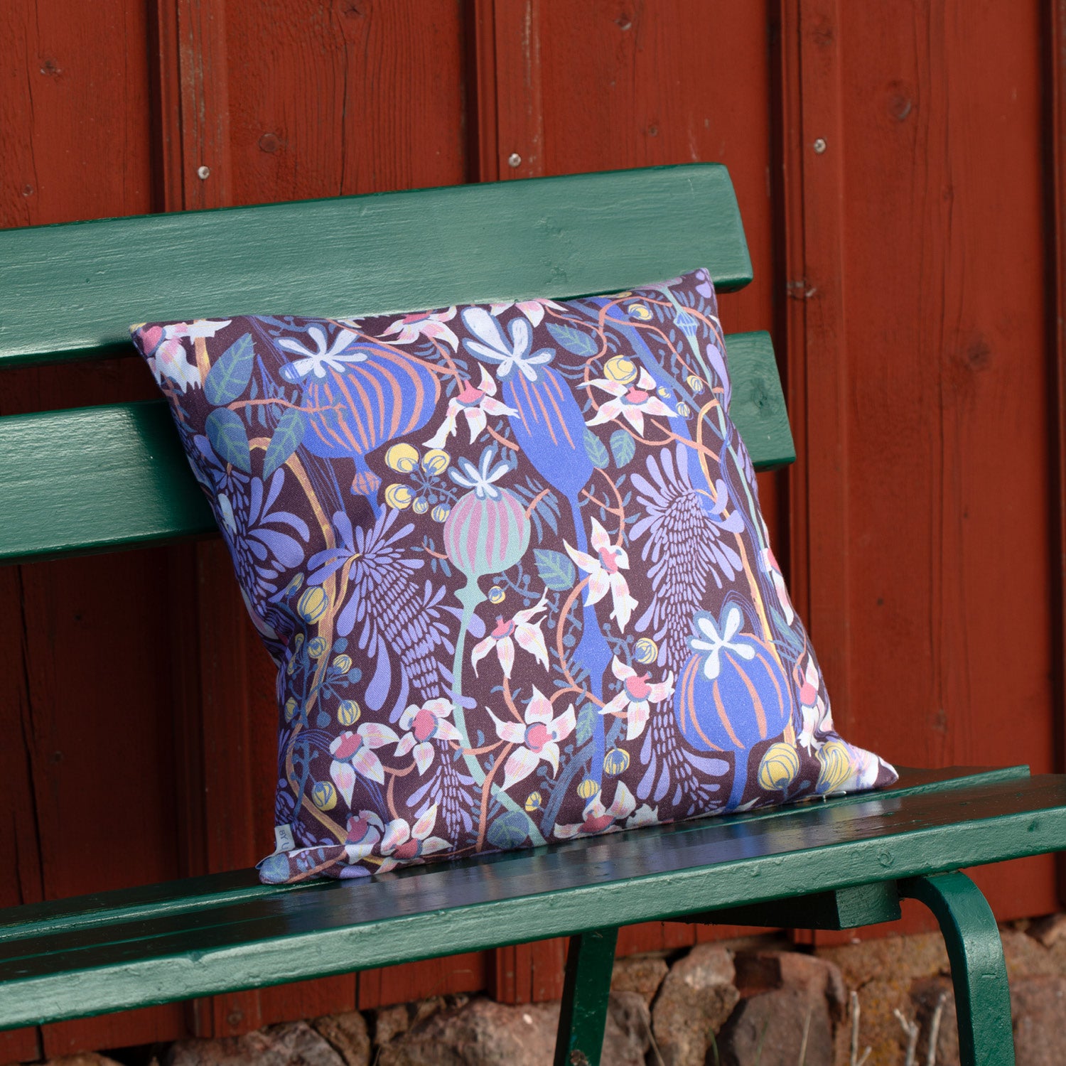 Blommig kudde på en bänk vid en röd vägg