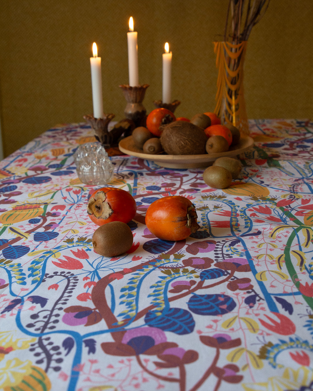 Blommigt tyg som duk på ett bord dukat med fruktfat och levande ljus