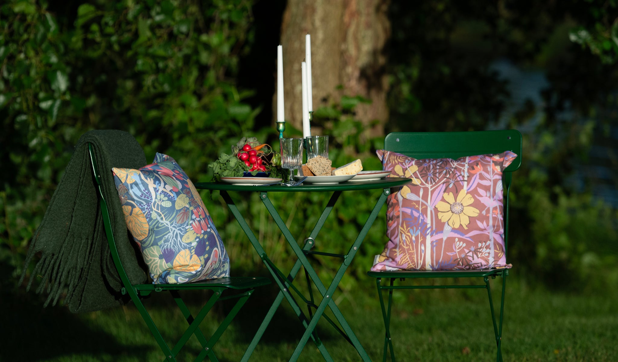 Två mönstrade blommiga kuddar i storleken 45x45cm vid dukat bord i trädgården svensk design av By Ulrika G