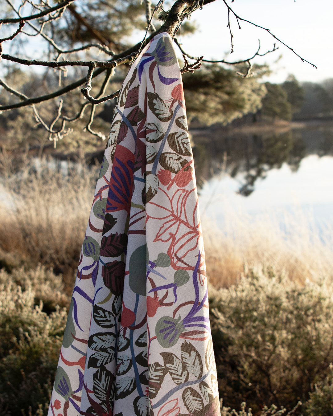 Blommigt mönstrat tyg som hänger på en gren i skogen vid sjön