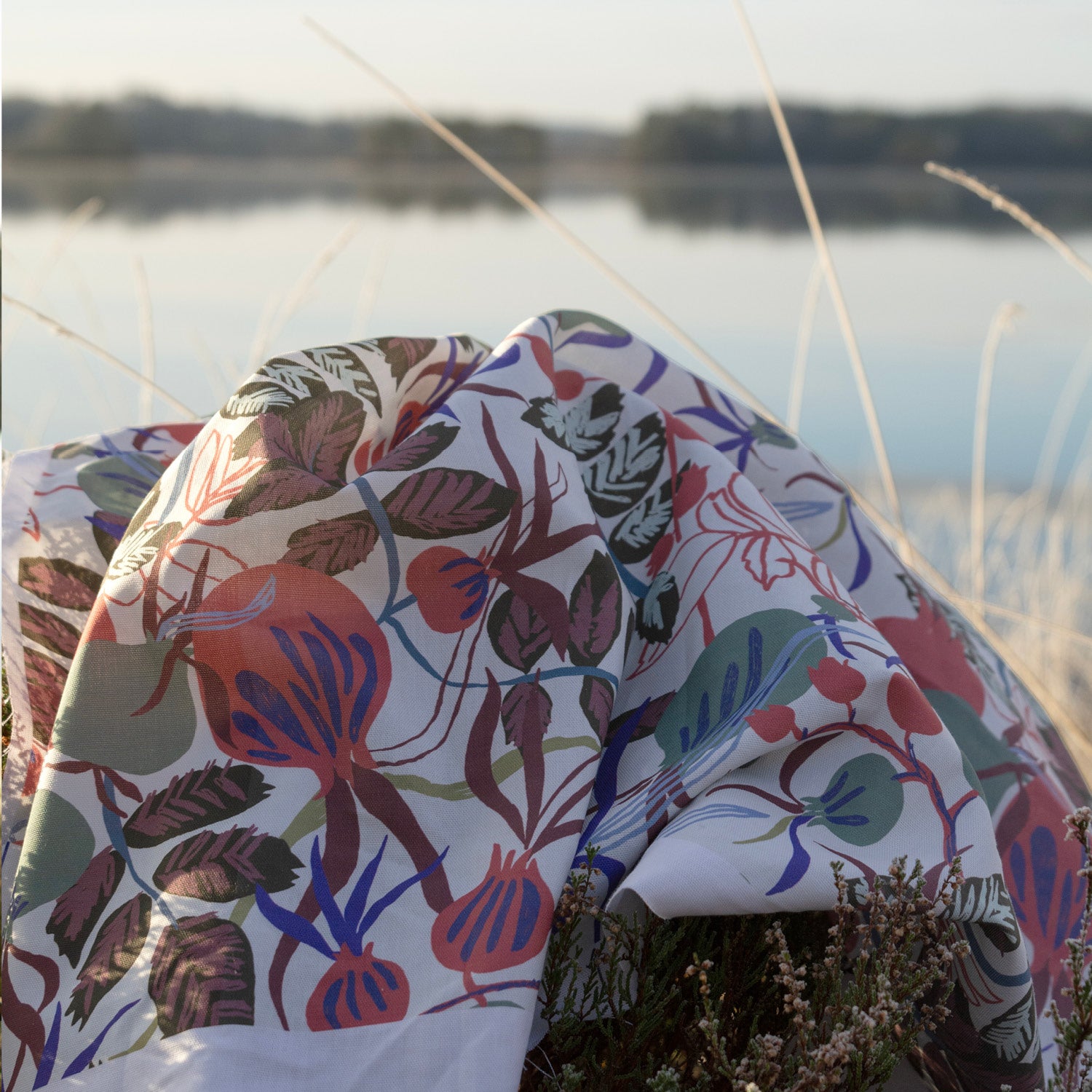 Blommigt mönstrat tyg som ligger ute i skogen vid sjön