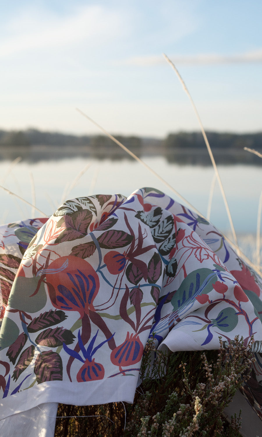Blommigt mönstrat tyg som ligger p stranden vid sjön
